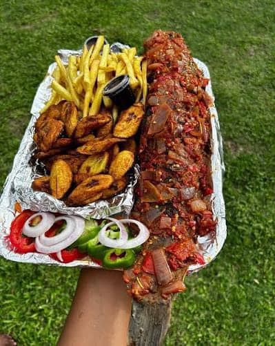 Whole grilled fish, heavily coated with pepper/onion seasoning French fries Fried ripe plantain (dodo) Fresh onions and peppers A small cup of dipping sauce